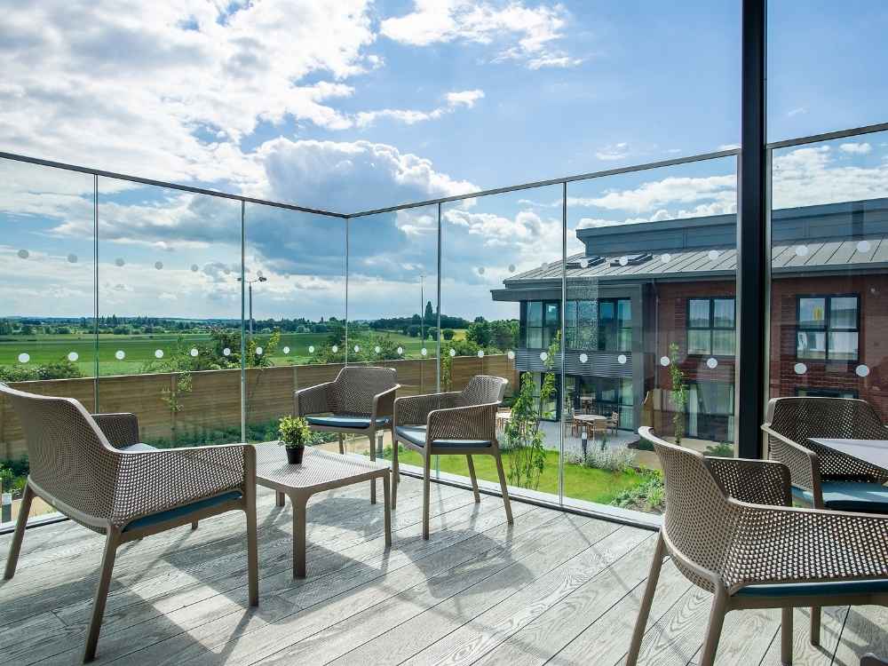 Glass-fronted balcony at Edwalton Manor Care Home in Nottingham overlooking landscaped gardens and surrounding countryside