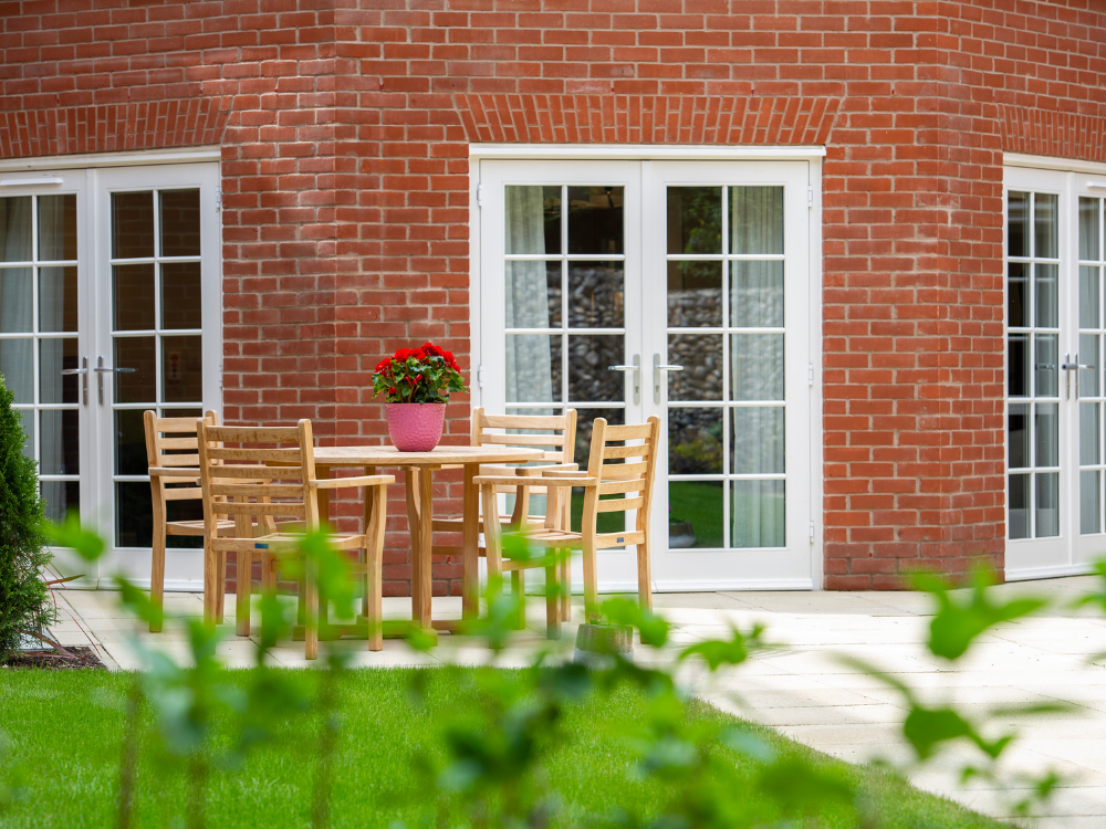 well kept green lawn with patio area and wooden table and chairs