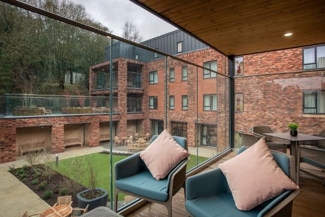Covered balcony seating area at Cofton Park Manor Care Home in Birmingham overlooking landscaped gardens and shared outdoor spaces
