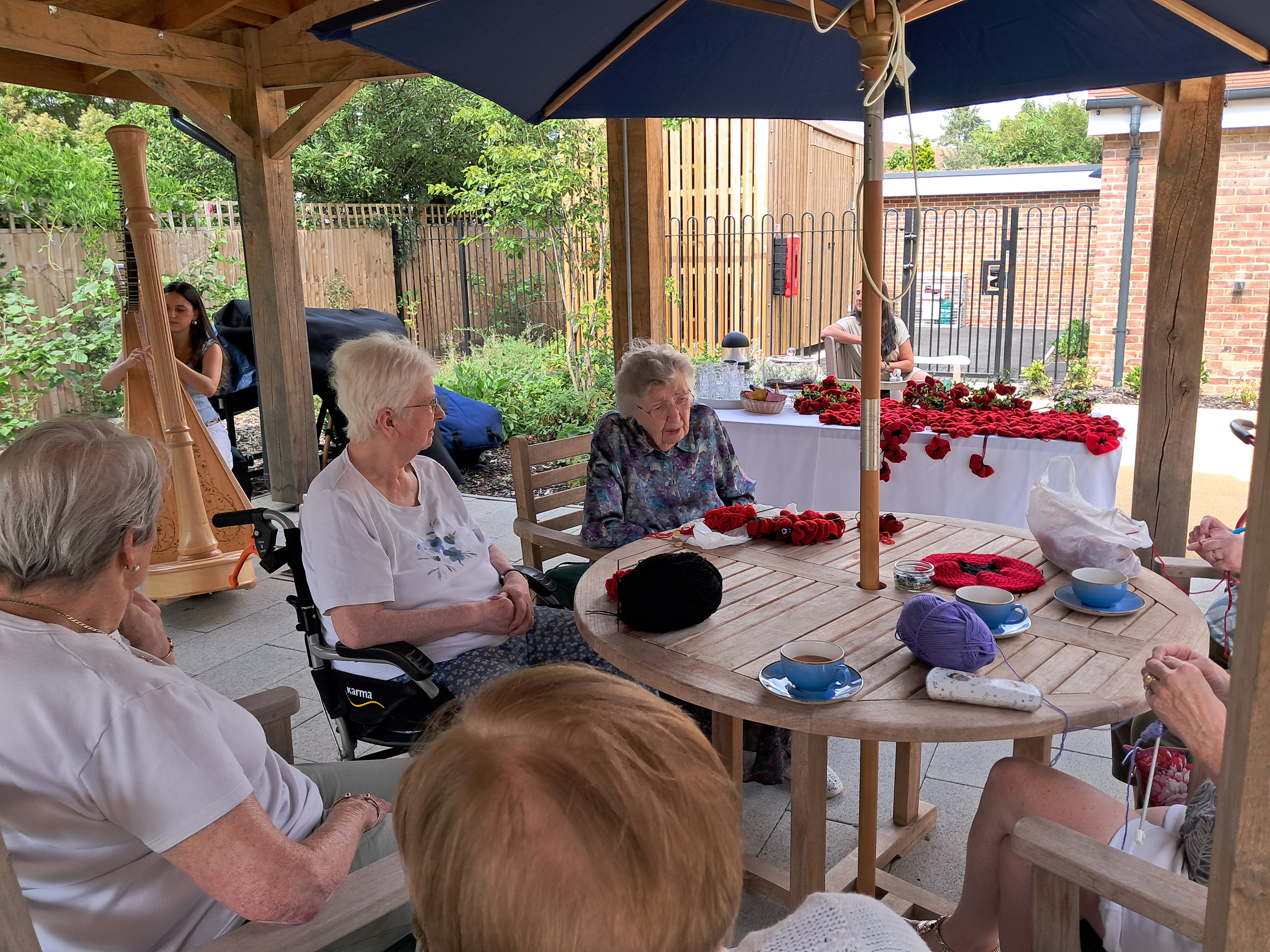 Residents at outside tables knitting red poppies